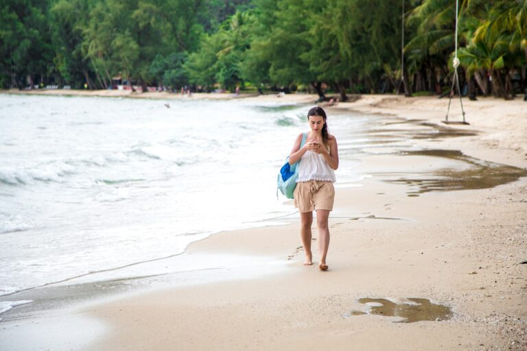 girl walking on the beach with the phone